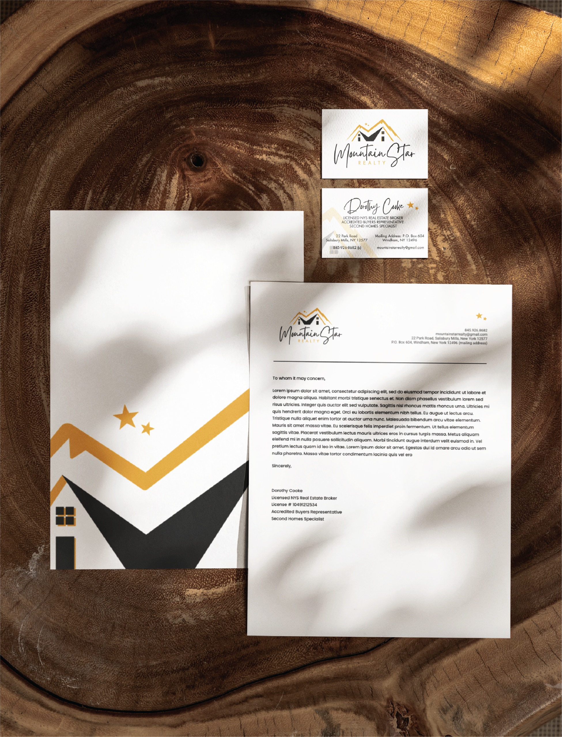 stationery design for realtors | Moonlit Media LLC A branded stationery design set on a wooden surface includes a letterhead, envelope, and business cards with a mountain logo, gold and black accents, and star motifs, featuring the name Mountain City—ideal for any Michigan general contractor.