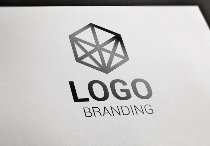A geometric, black hexagonal logo with intersecting lines—created using AI-Generated Logos—appears above the bold word LOGO and the lighter word BRANDING, all printed on a white paper surface.