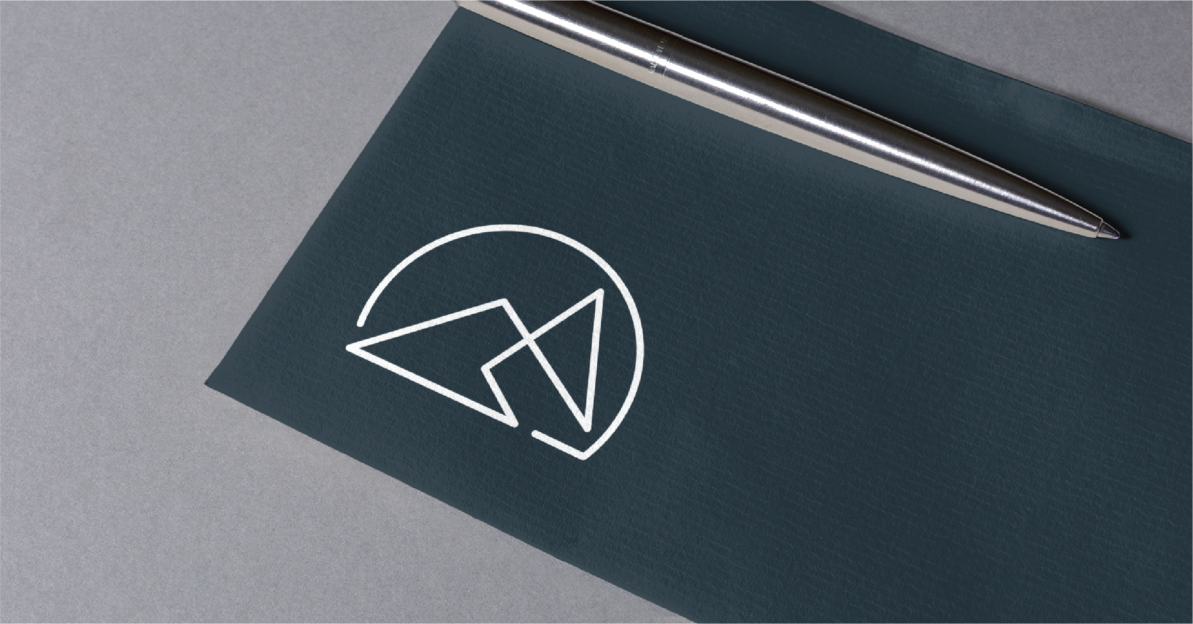 A silver pen rests on a dark blue envelope featuring a white, minimalist mountain logo—perfect inspiration for business card design in Michigan—placed on a light gray surface.