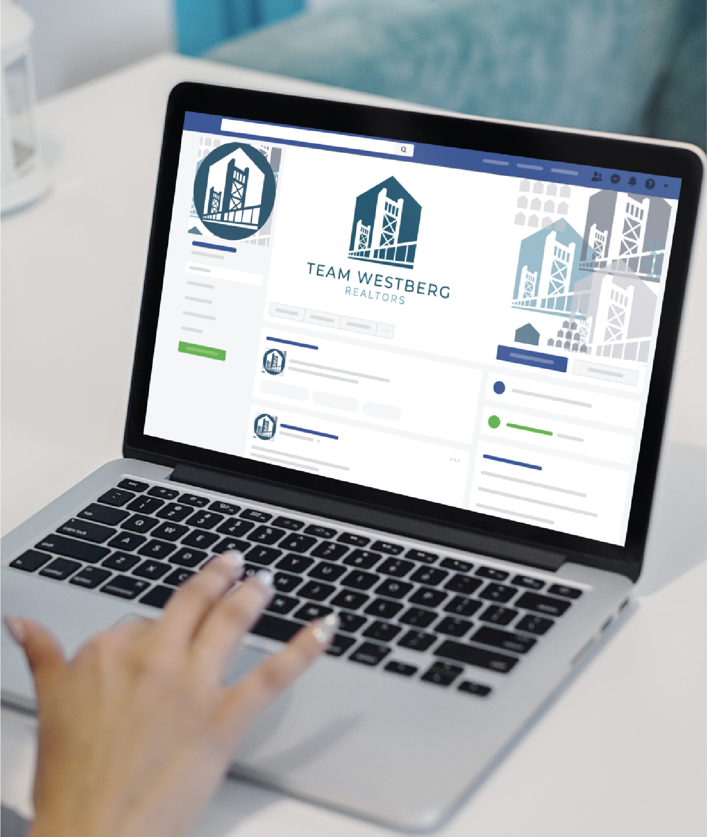 A hand rests on a laptop touchpad, displaying a Facebook business page for Team Westberg Realtors, featuring Social Graphics and a blue and gray cityscape logo inspired by California on the screen.