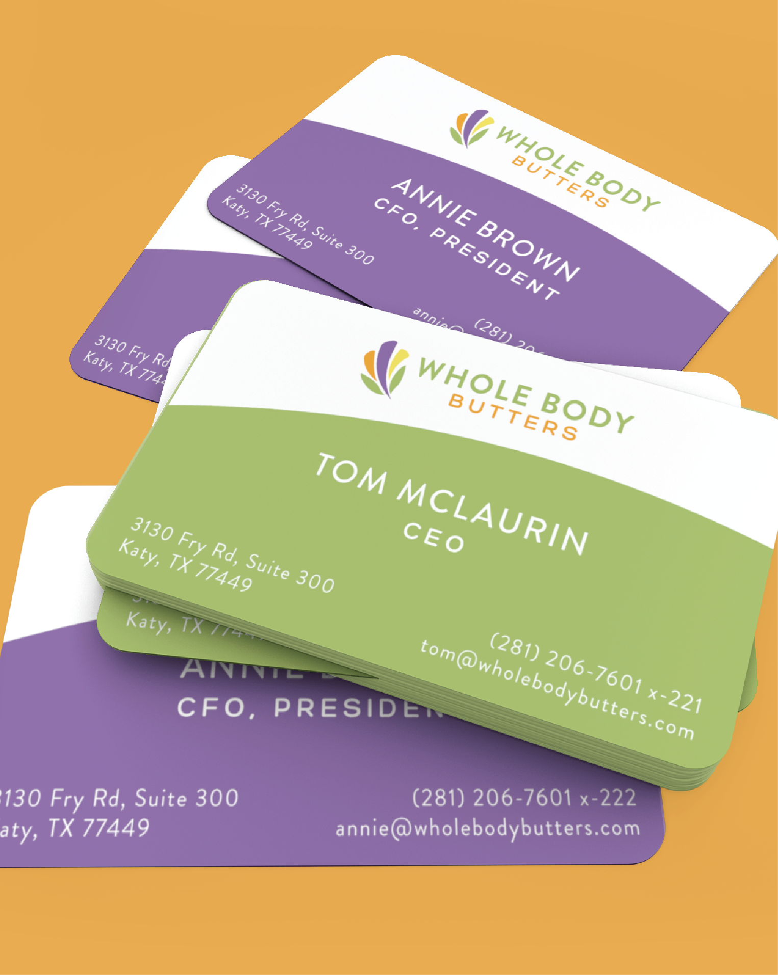 A stack of Whole Body Butters business cards on an orange surface, featuring custom print designs in green and purple for Tom McLaurin (CEO) and Annie Brown (CFO, President), crafted in New York.