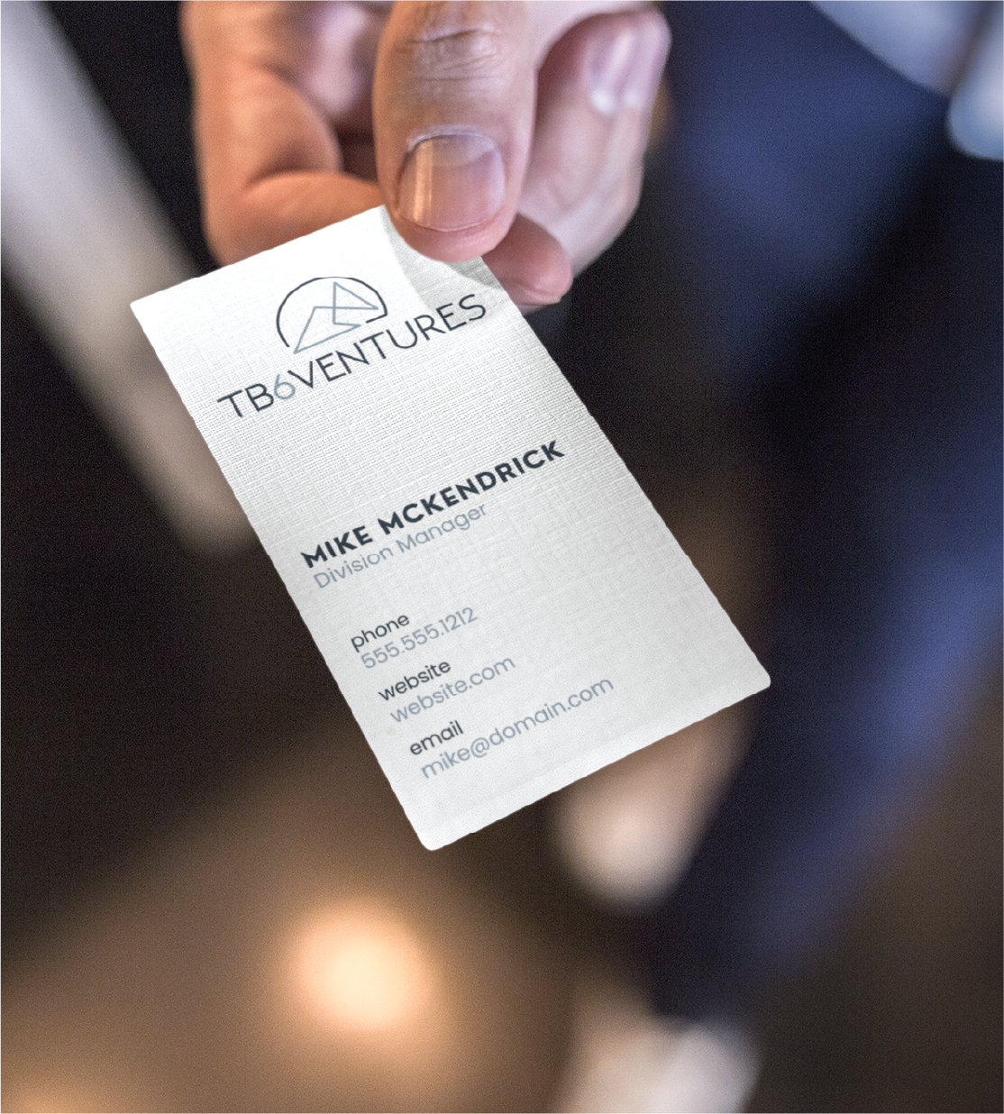 A hand holds a Professional Business Card for TB6 Ventures. The card displays the company logo, name, and Mike McKendrick's details as Division Manager, highlighting quality Business Card Design for top Business Service Michigan firms.