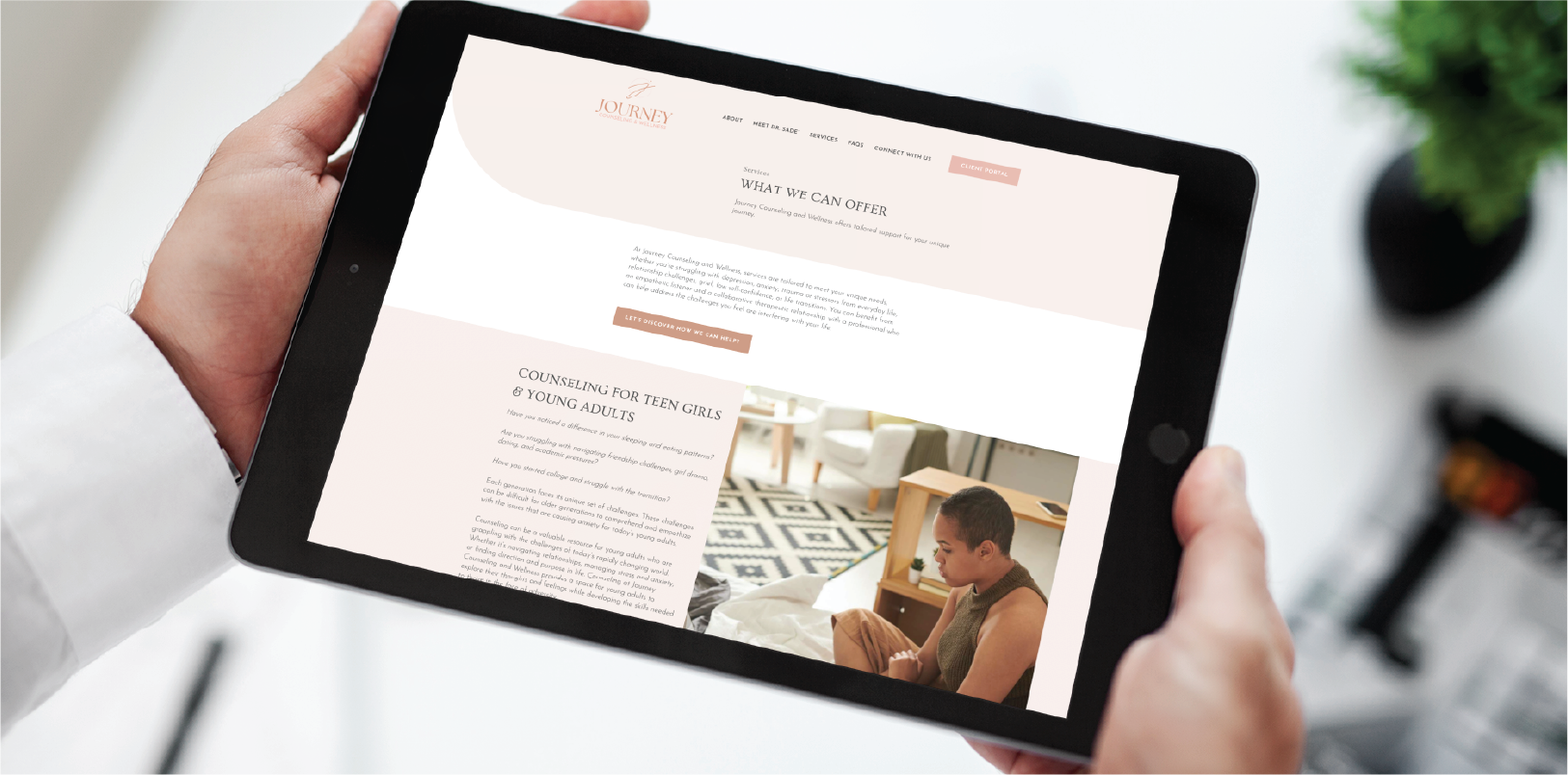 A person holds a black tablet displaying a custom website design for counseling services in Georgia, featuring soft pink tones and an image of a young woman sitting thoughtfully on a bed.