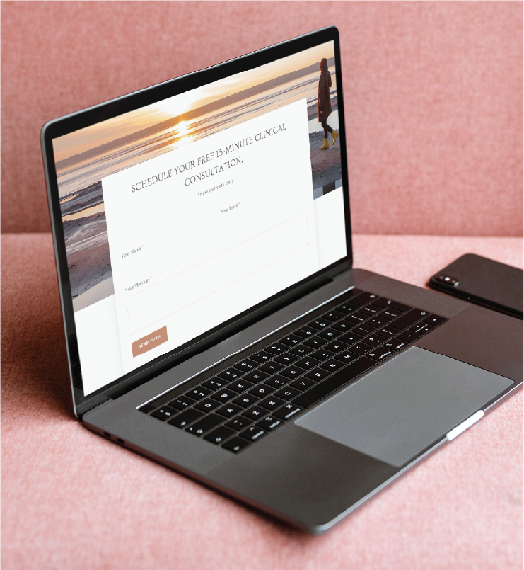 A laptop on a pink couch displays a website form offering a free 15-minute clinical consultation for Counseling Services in Georgia. A smartphone is placed next to the laptop.