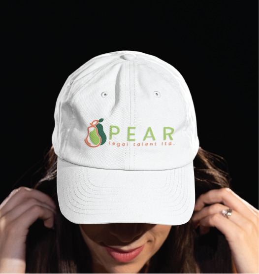 A person wearing a white baseball cap with a logo that includes a pear graphic and the words PEAR legal talent ltd., a Toronto legal recruitment firm, embroidered on the front. The background is dark.