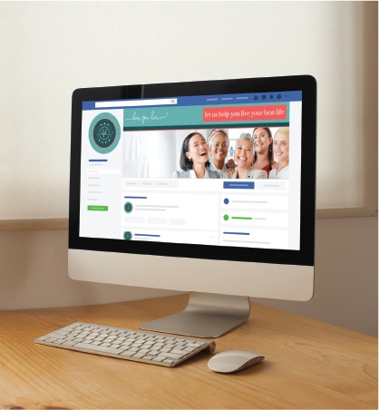 A computer on a wooden desk displays a social media design for a Pennsylvania skincare brand, featuring a group of smiling women in the cover photo, with light streaming in from a window behind.