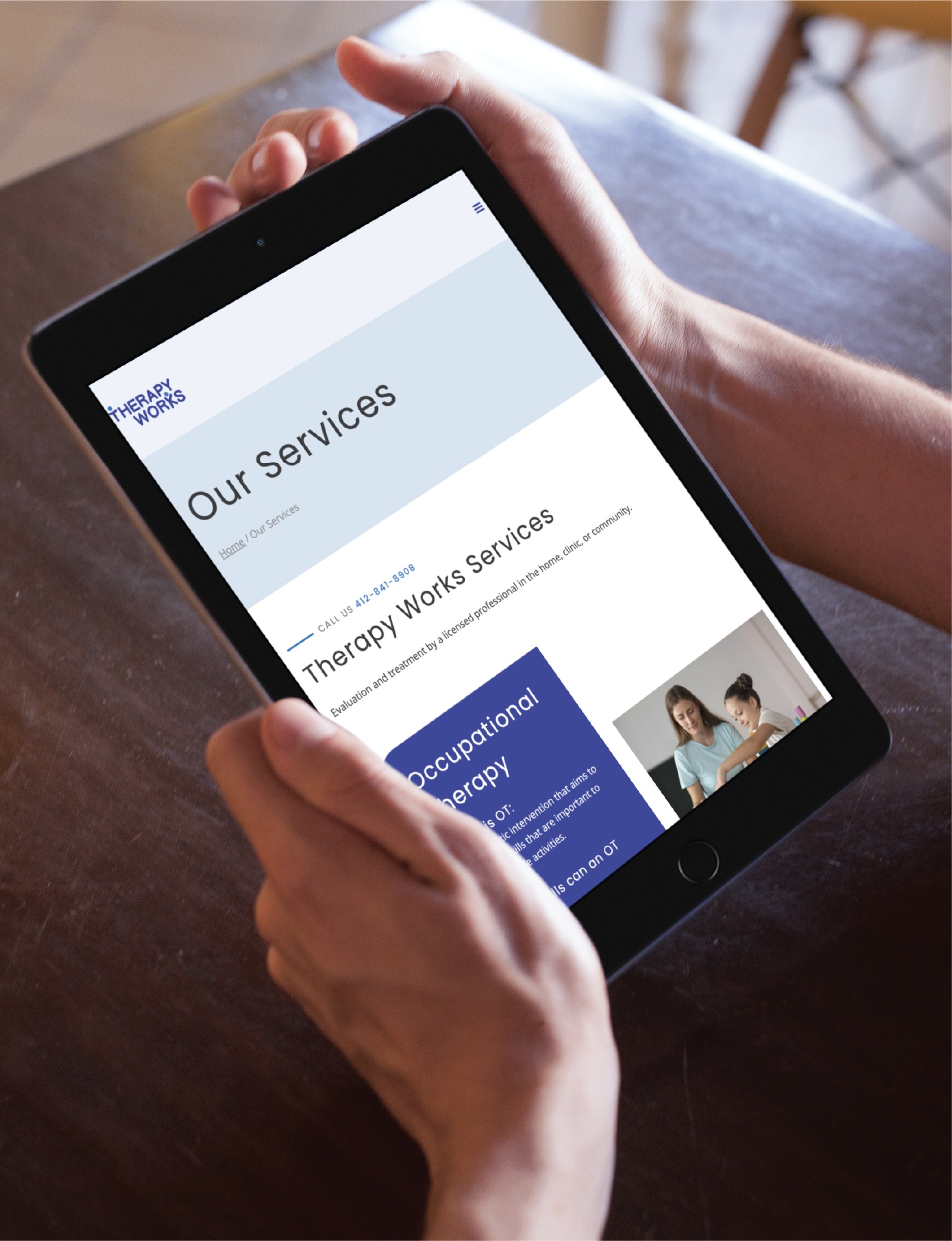 A person holds a tablet displaying a beautifully designed website page titled Our Services for Therapy Works, featuring youth therapy services in Pennsylvania and a photo of two women in conversation.
