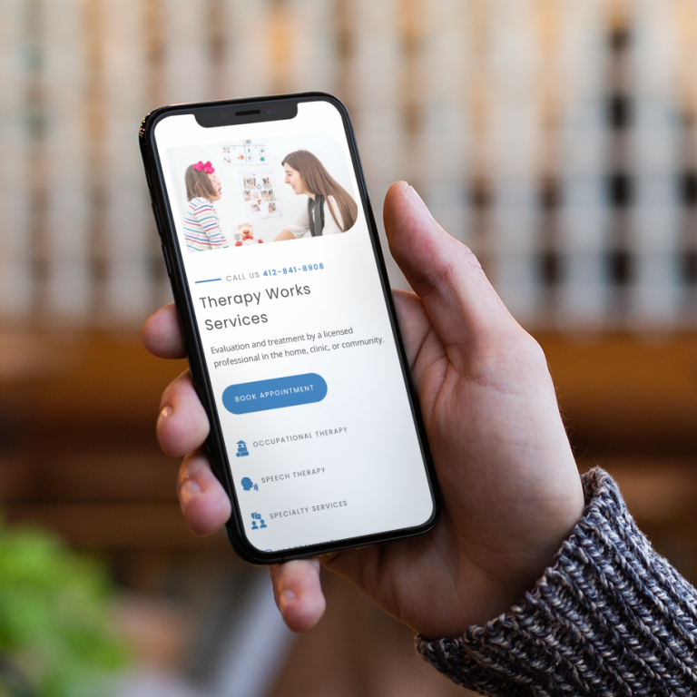 A person holds a phone displaying a thoughtfully crafted website for therapy services in Pennsylvania, featuring a prominent “Book Appointment” button and icons for occupational, speech therapy, and specialty care.