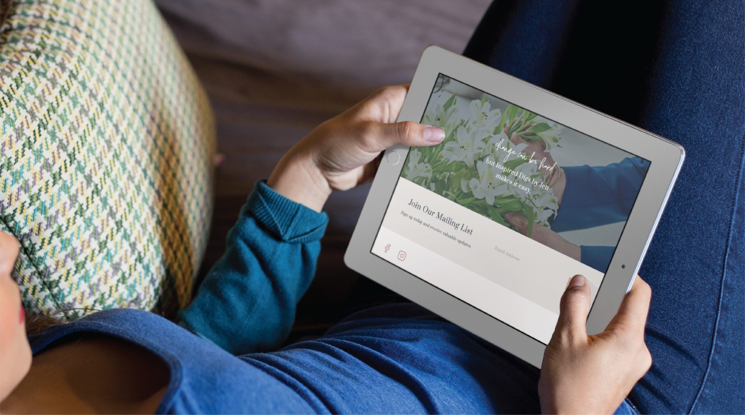A person in a blue sweater is lying on a couch and holding a white tablet, browsing a web design site from Texas that features a floral image and text about joining a mailing list.
