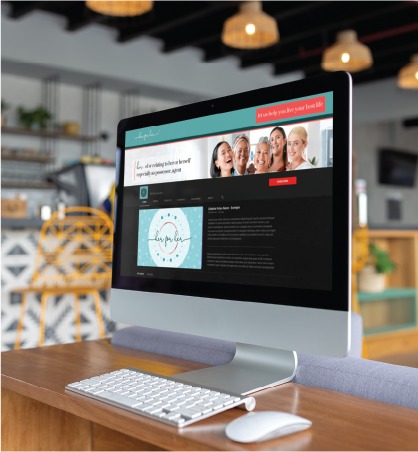 A desktop computer on a wooden desk displays a website with a banner of smiling people, expertly showcasing Social Media Design for a Skincare Brand. The background shows a modern, cozy café with chairs, tables, and hanging lights—an inviting scene that could easily be found in Pennsylvania.