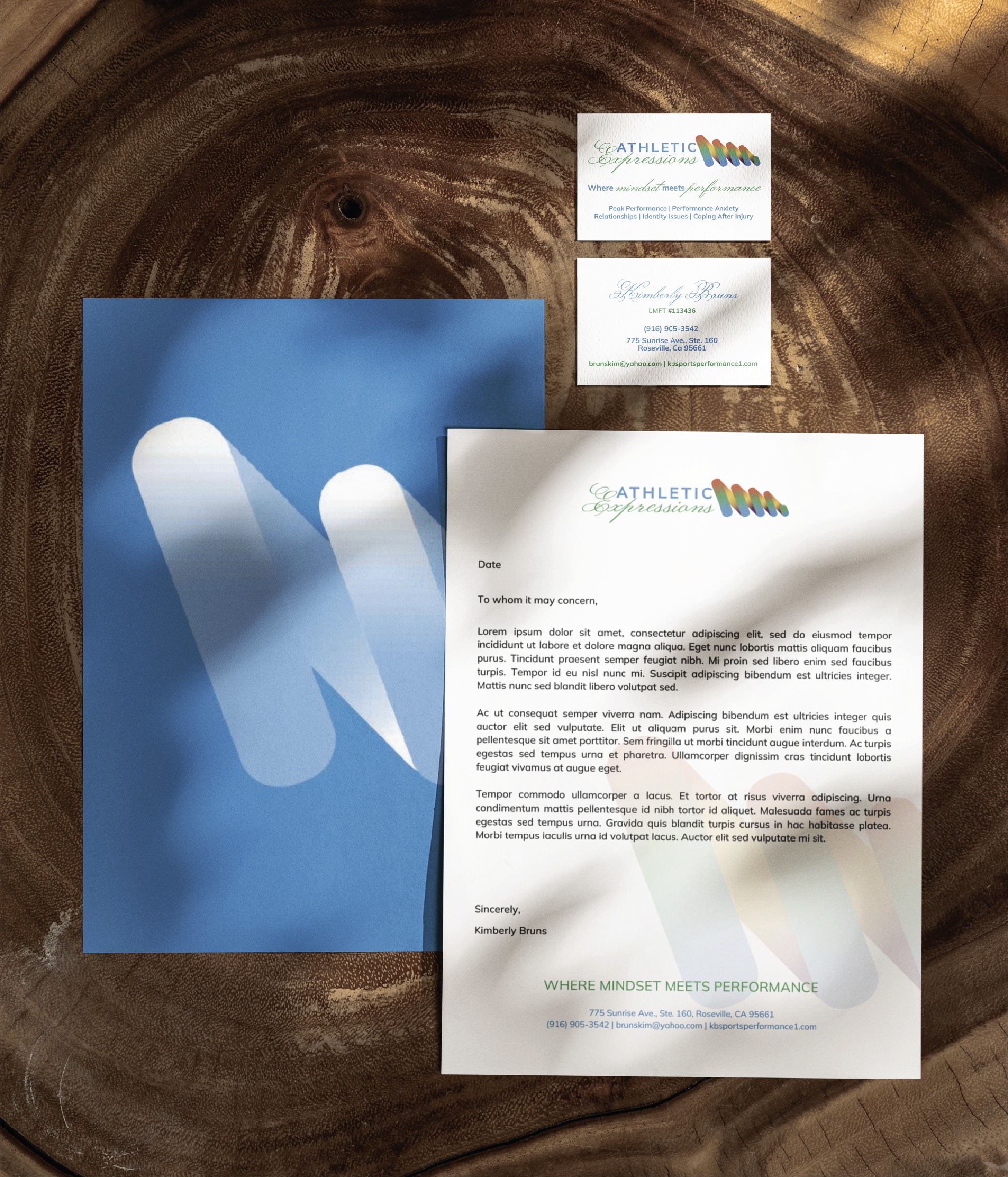 Wooden textured background with scattered white business cards and a letter, featuring a colorful logo and the text'Athletic Expressions' or 'Where minds meet performance' nearby.