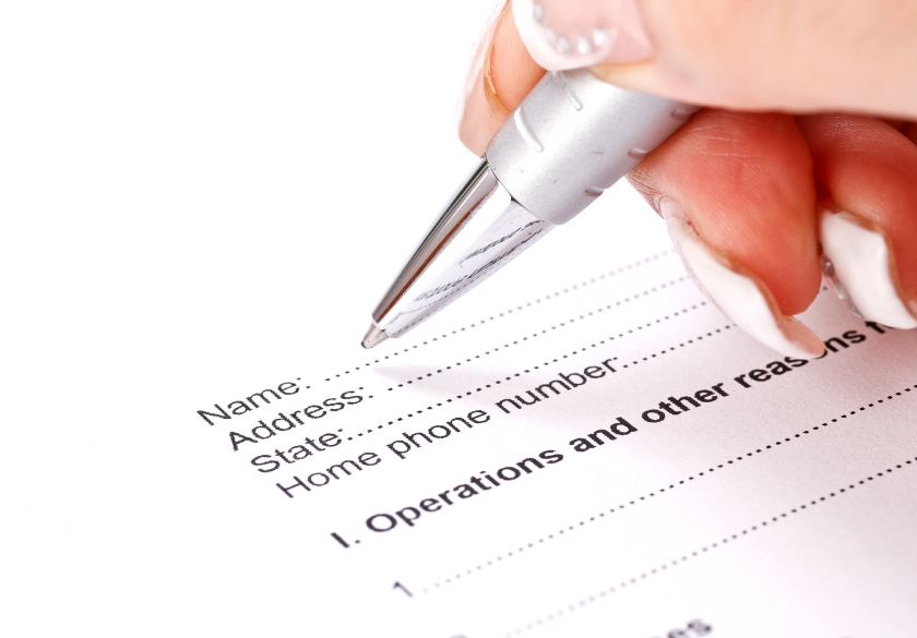 A hand with white nail polish holds a pen, filling out a form that asks for name, address, state, and home phone number—perfect for the new patient page on your medical practice website.