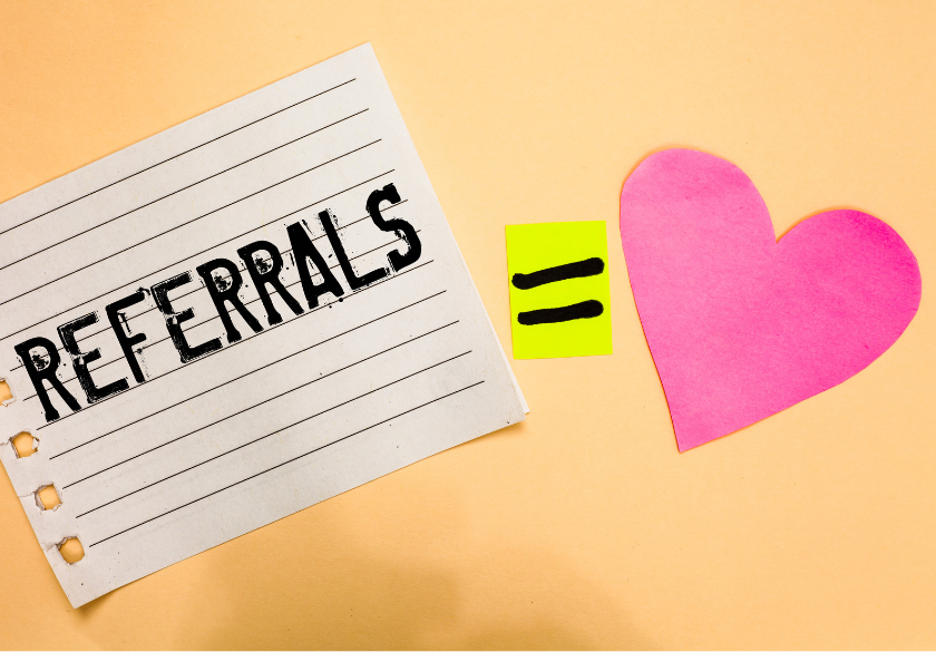 A note with REFERRALS written on it, an equals sign on a yellow paper, and a pink heart on a peach background, symbolizing that customer referrals are valued or appreciated.