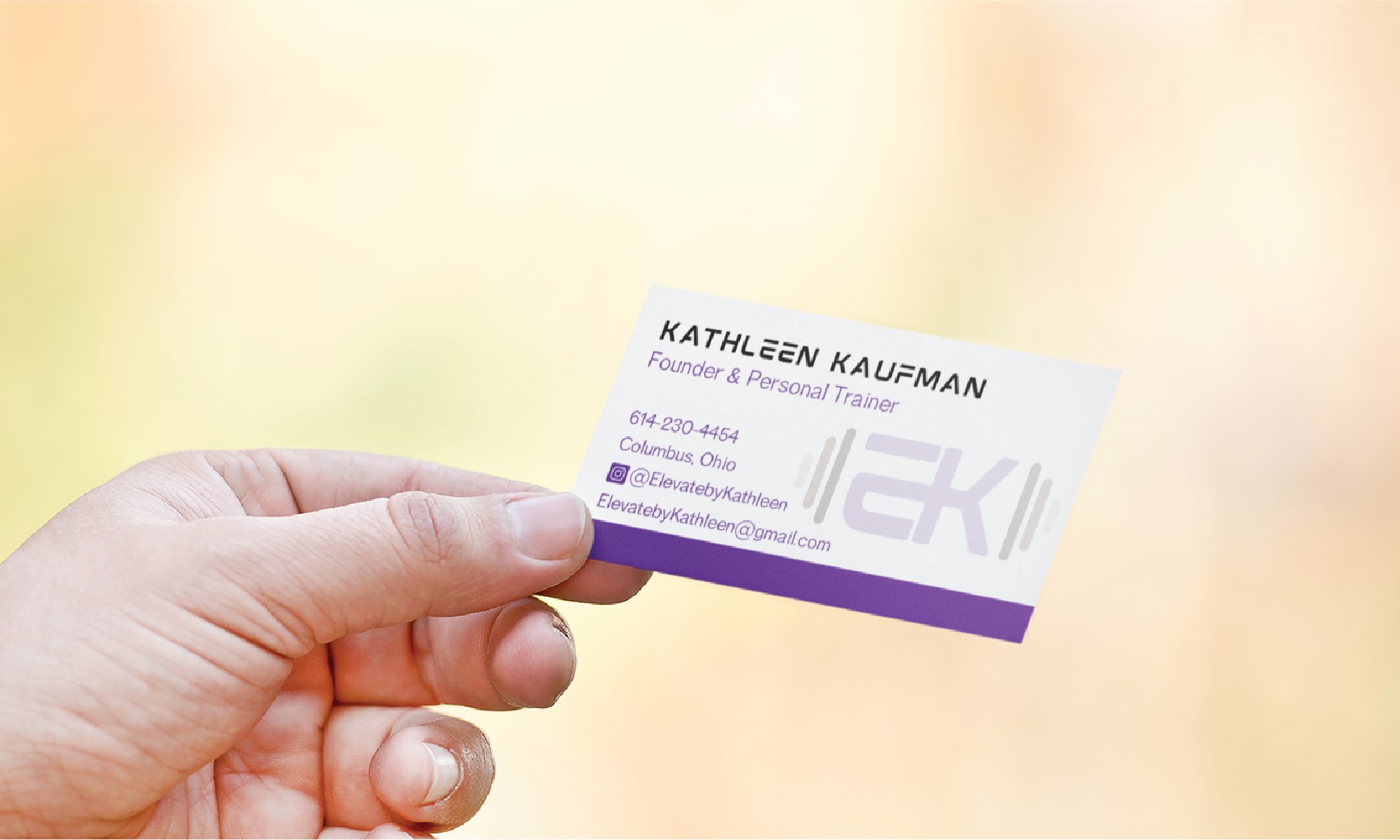 A hand holds a business card for Kathleen Kaufman, Founder & Personal Trainer in Ohio, featuring a modern stationery design with contact details, email, and social media info on a blurred outdoor background. The card is white with purple accents and a logo.