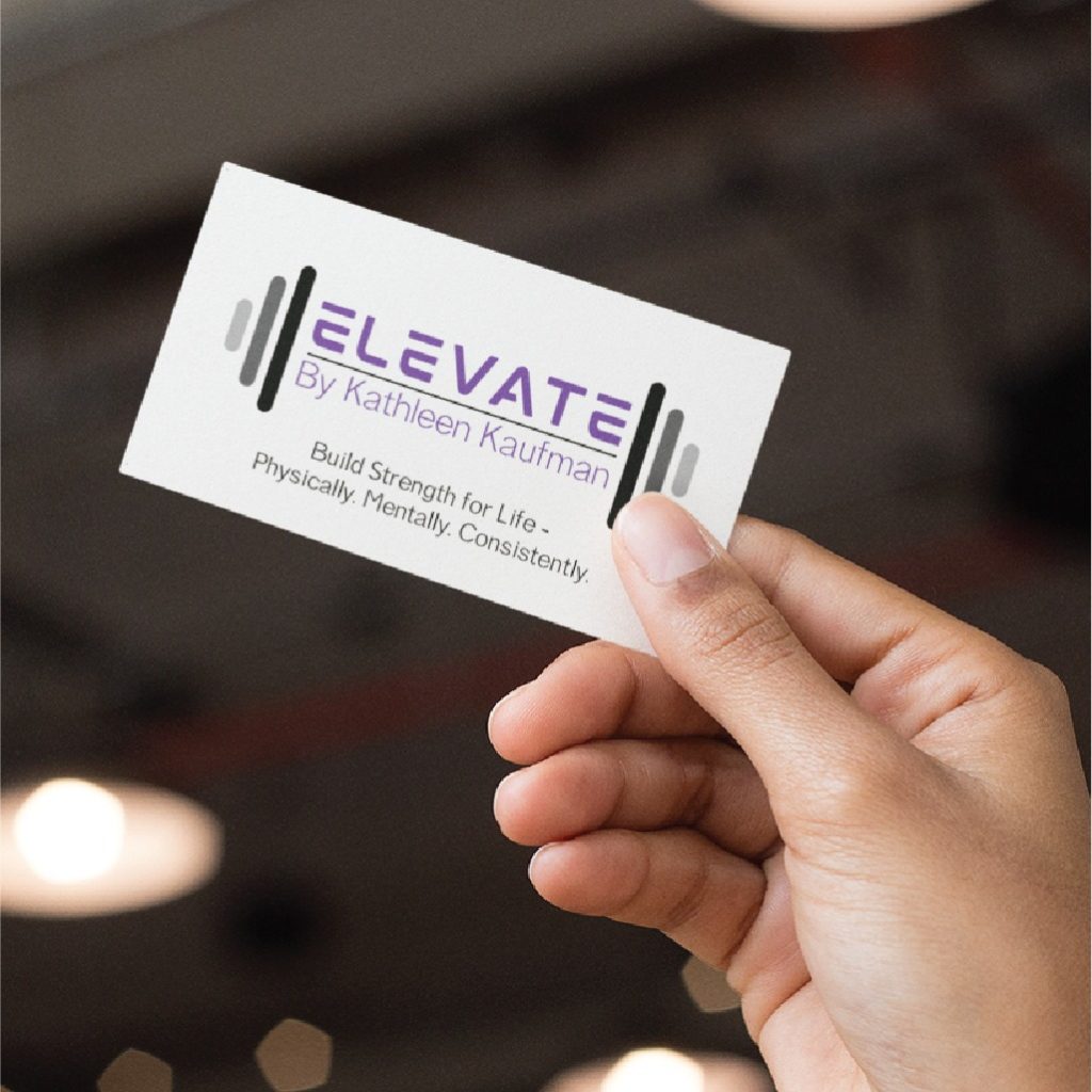 A hand holds a business card featuring professional stationery design for Elevate by Kathleen Kaufman, a Personal Trainer based in Ohio. The card showcases a barbell graphic alongside the slogan: Build Strength For Life. Physically. Mentally. Consistently.