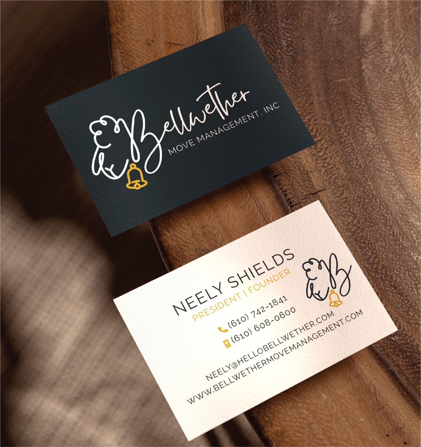 Two Bellwether Move Management business cards on wood; one is dark with a white logo of a sheep and bell, the other is light with contact info, name Neely Shields, and the same sheep logo in gold and black. A refined example of print design, these cards reflect Bellwether’s professional presence in California’s nonprofit housing industry.