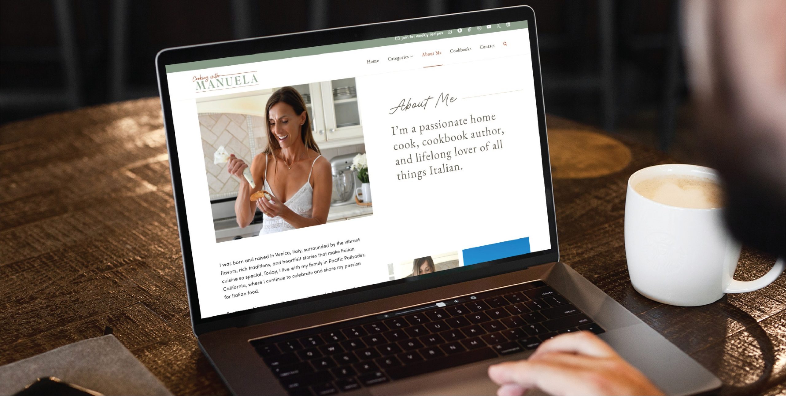 A person using a laptop views a beautifully custom website design featuring a woman cooking, with an About Me section describing her as a California home cook, cookbook author, and lover of Italian food. A cup of coffee sits nearby.