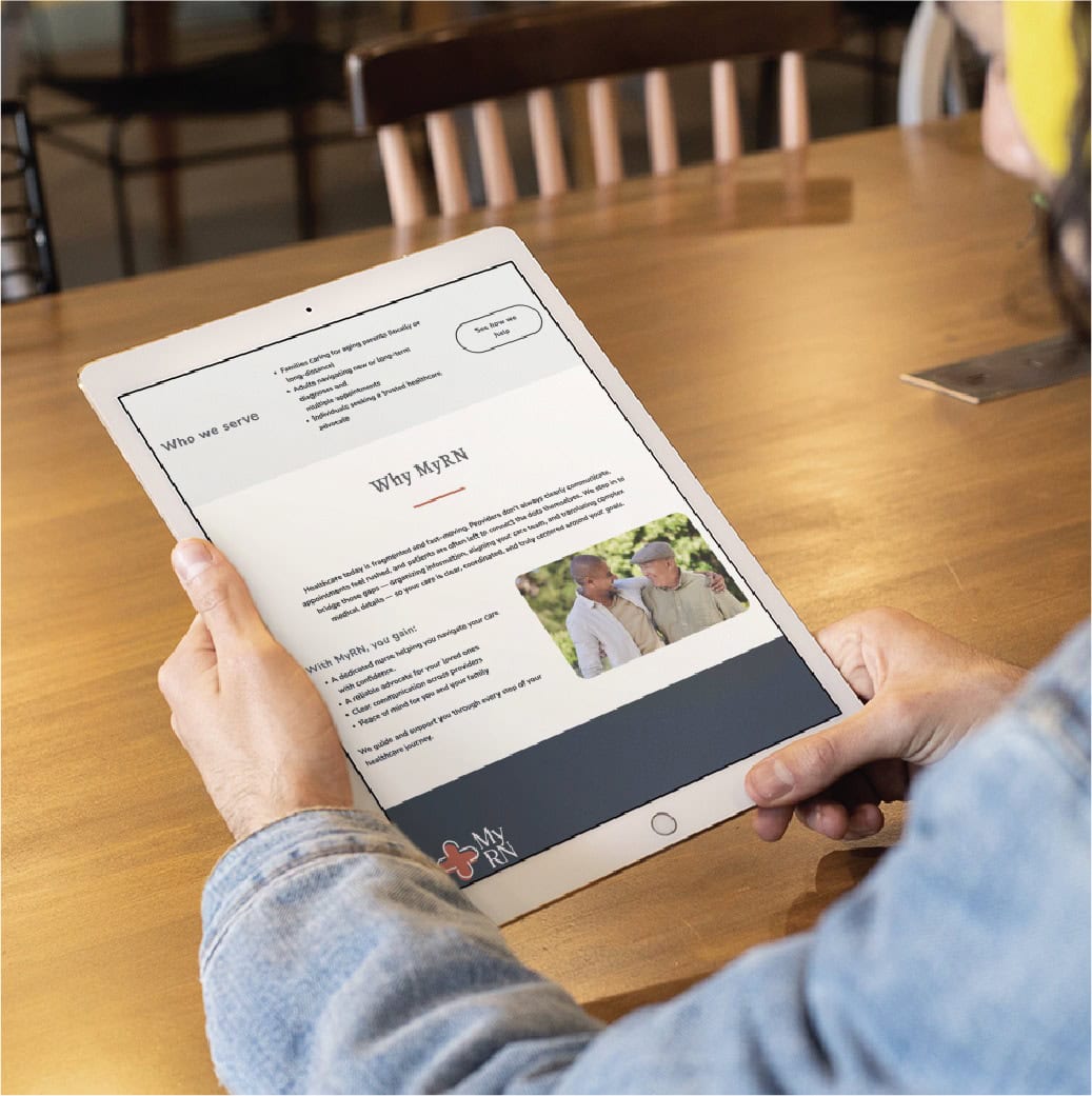 A person holds a tablet displaying a webpage about Why MyPAN, featuring an image of two people outdoors in Minnesota and text describing the service. The tablet rests on a wooden table with chairs in the background, highlighting thoughtful website design that captures the spirit of RN Services.