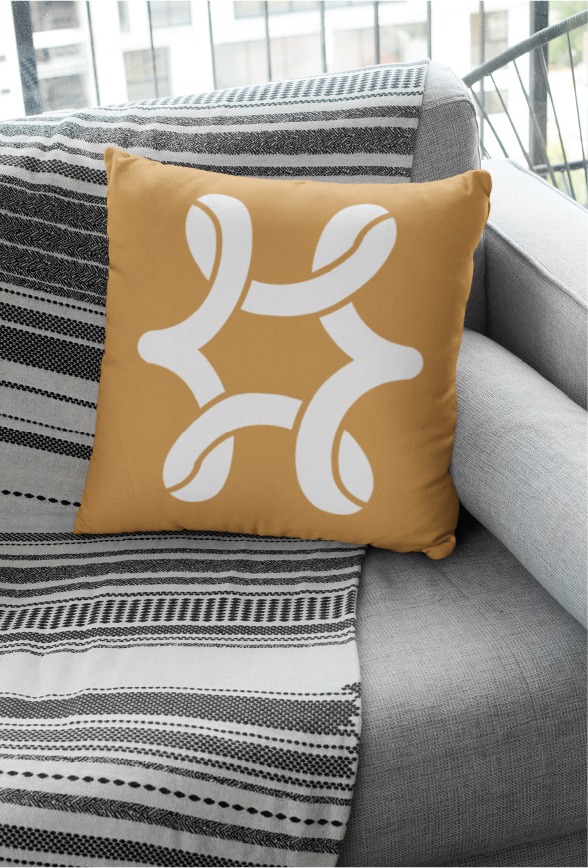 A mustard-colored pillow with a bold white abstract geometric design rests on a gray sofa draped with a black and white striped blanket, near a window—inviting the creative energy of New Orleans into your home, much like the innovation seen in Tulane University’s approach to website design.