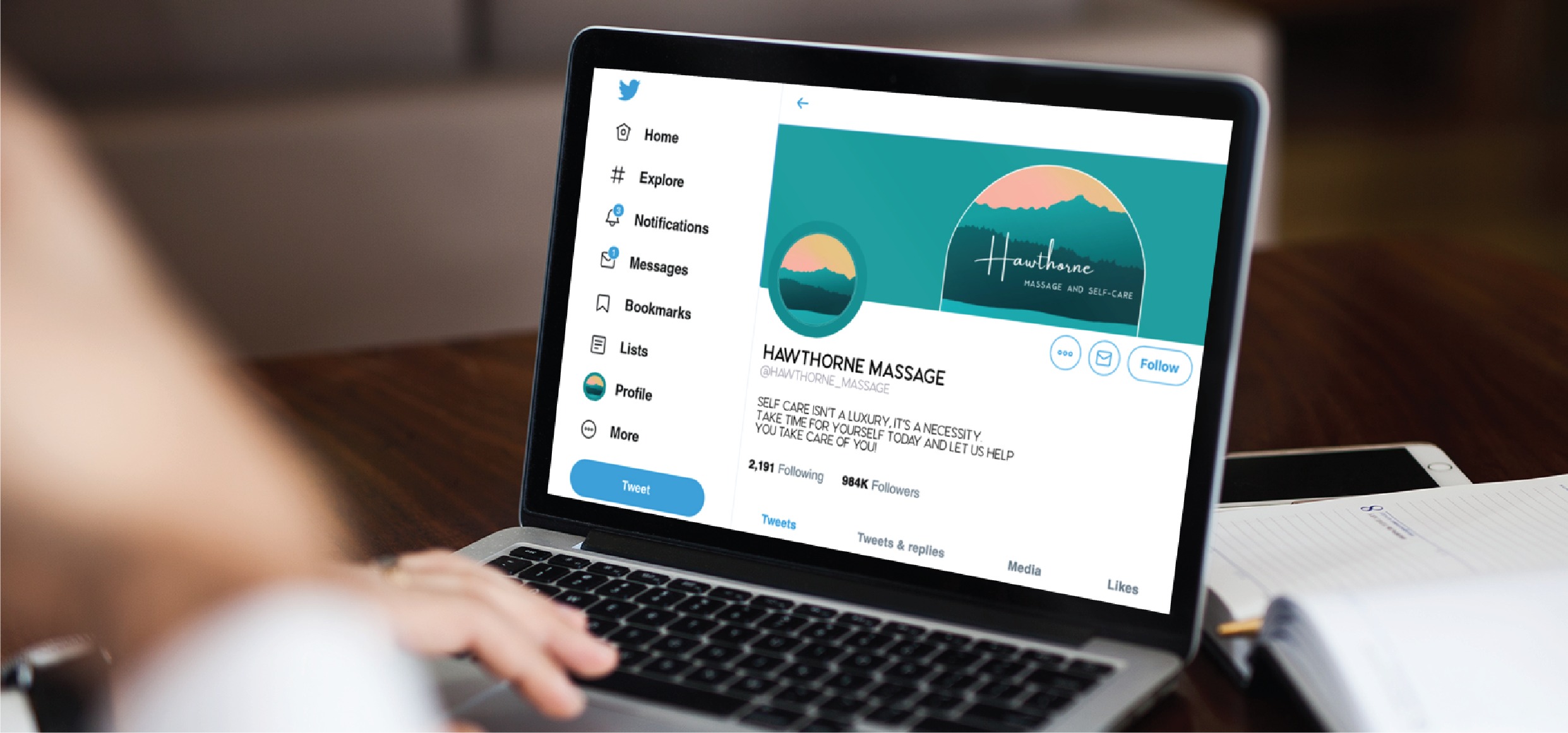 A person uses a laptop displaying a Twitter profile for Hawthorne Massage, a Pennsylvania business featuring a green and orange mountain logo and the bio: Self-care isn’t selfish. Let us help you take care of you. The clean social media design mirrors that of an inviting skincare brand, creating an atmosphere of calm and rejuvenation.