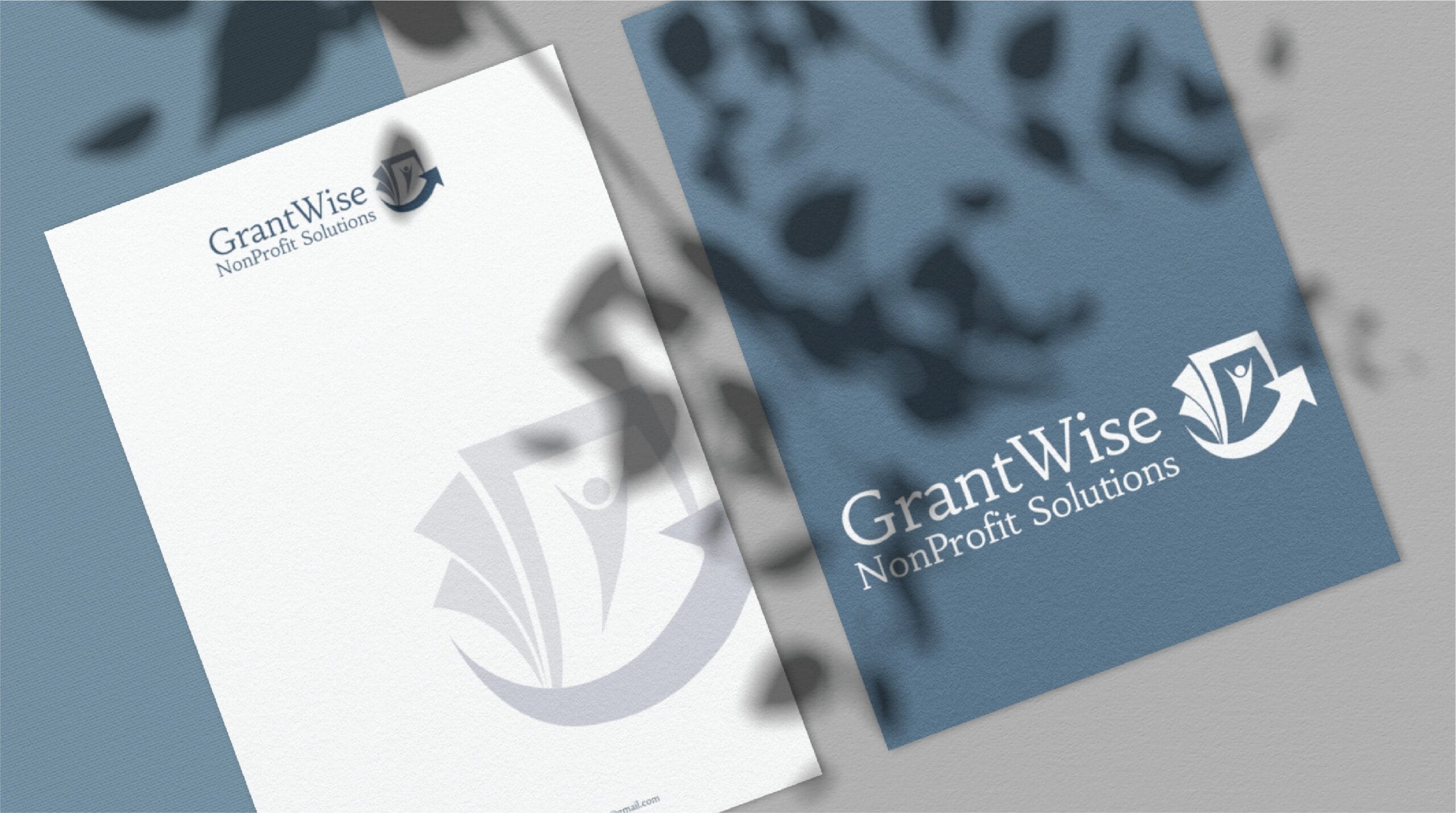 Two pieces of stationery for GrantWise NonProfit Solutions are shown, featuring professional print design with a logo displaying a stylized person, book, and arrow. One is a white sheet and the other is a blue folder, with leaf shadows overlaying both — perfect for move management initiatives or any organization based in Pennsylvania.