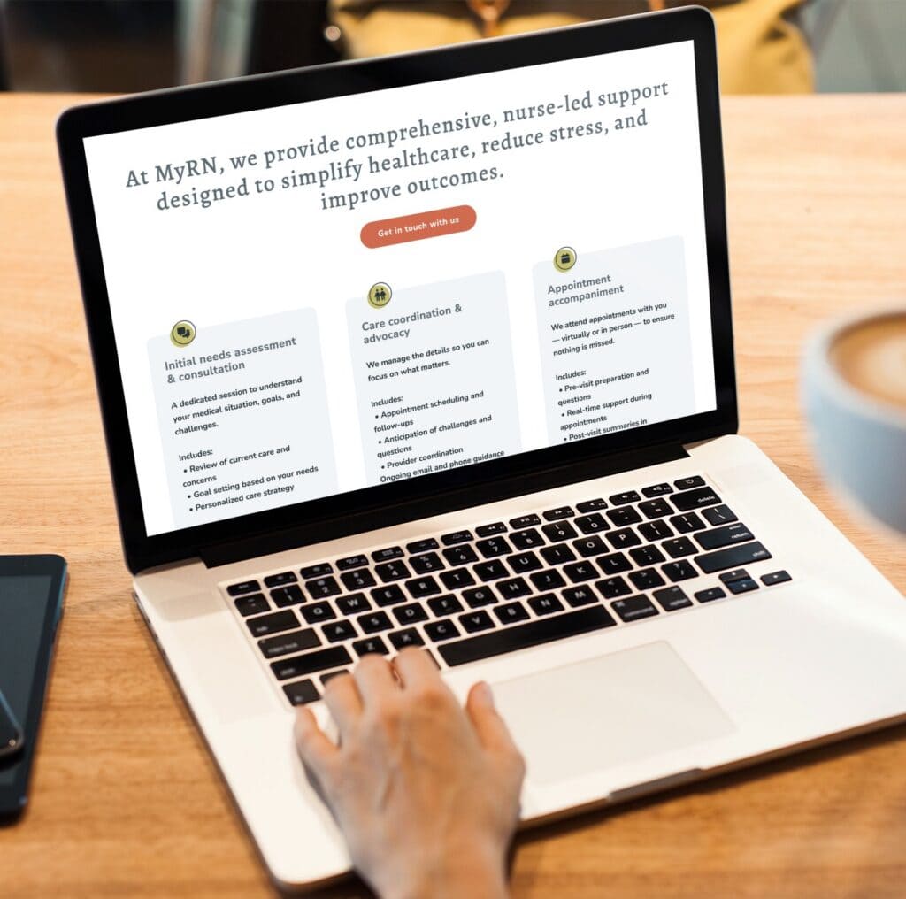 A person uses a laptop displaying a Minnesota-based website for MyRN, which offers RN Services such as nurse-led assessments, care coordination, and appointment help. A smartphone lies nearby on the wooden table, highlighting the thoughtful website design that makes accessing support easy across devices.