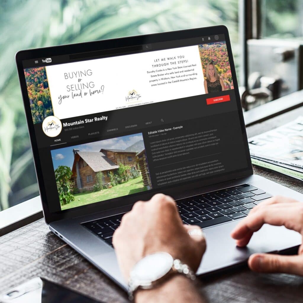 A person uses a laptop displaying a realty website with a cabin photo and a banner reading Buying & Selling your land or home? Mountain Star Realty. As the Michigan-based site showcases local listings, a keyboard and greenery are visible in the background.
