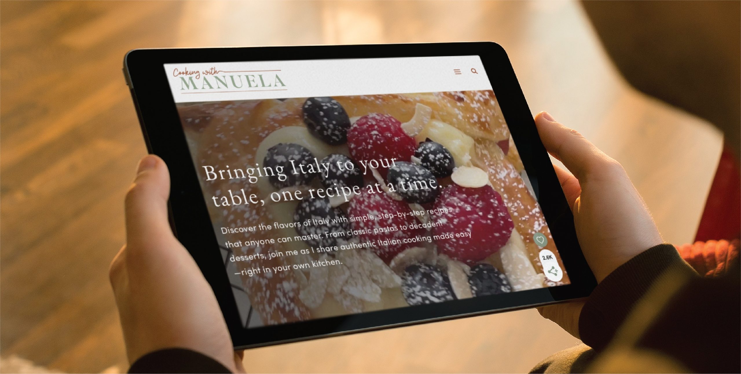 A person holds a tablet displaying a custom website design for a cooking website with a berry dessert in the background and the text, Bringing Italy to your table, one recipe at a time—a perfect inspiration for any California home cook.