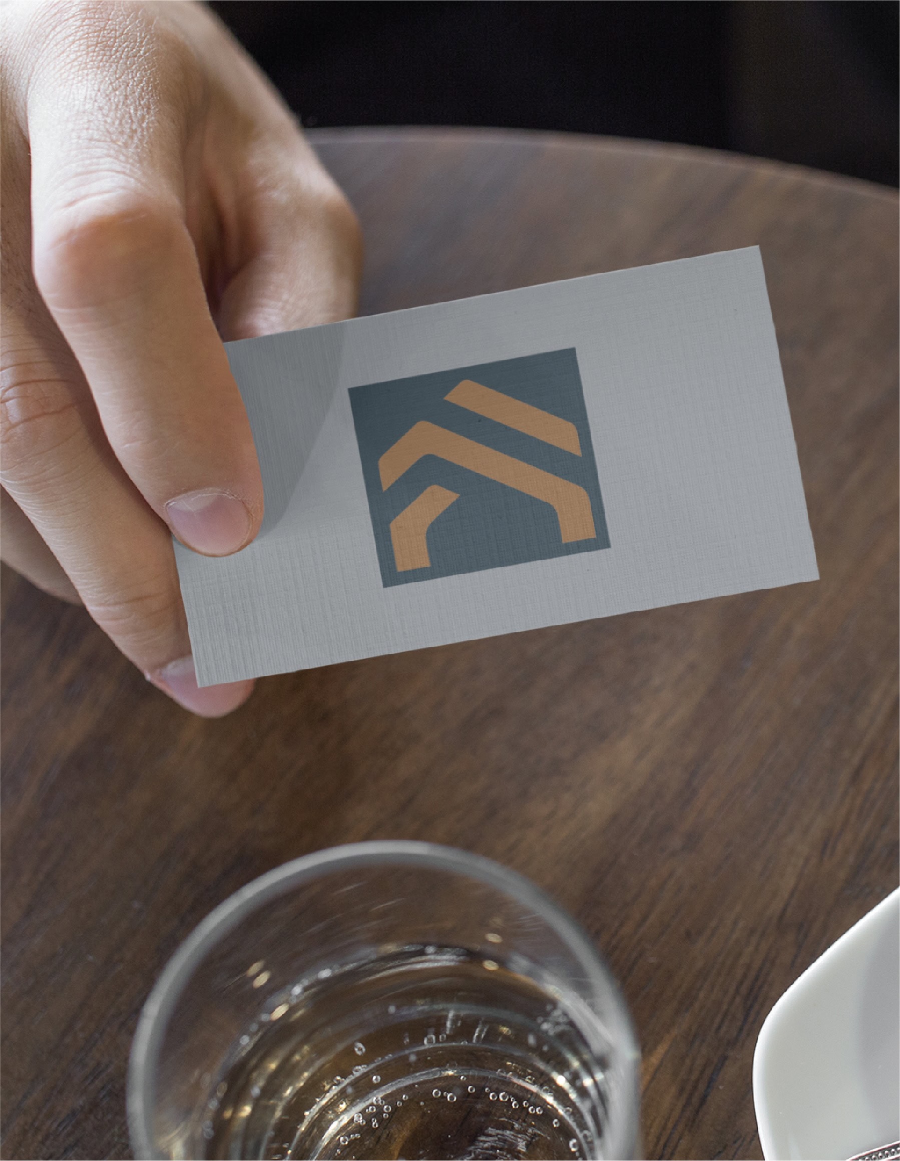 A hand holds a Construction CPA business card displaying a logo of a golden house silhouette on a dark square.