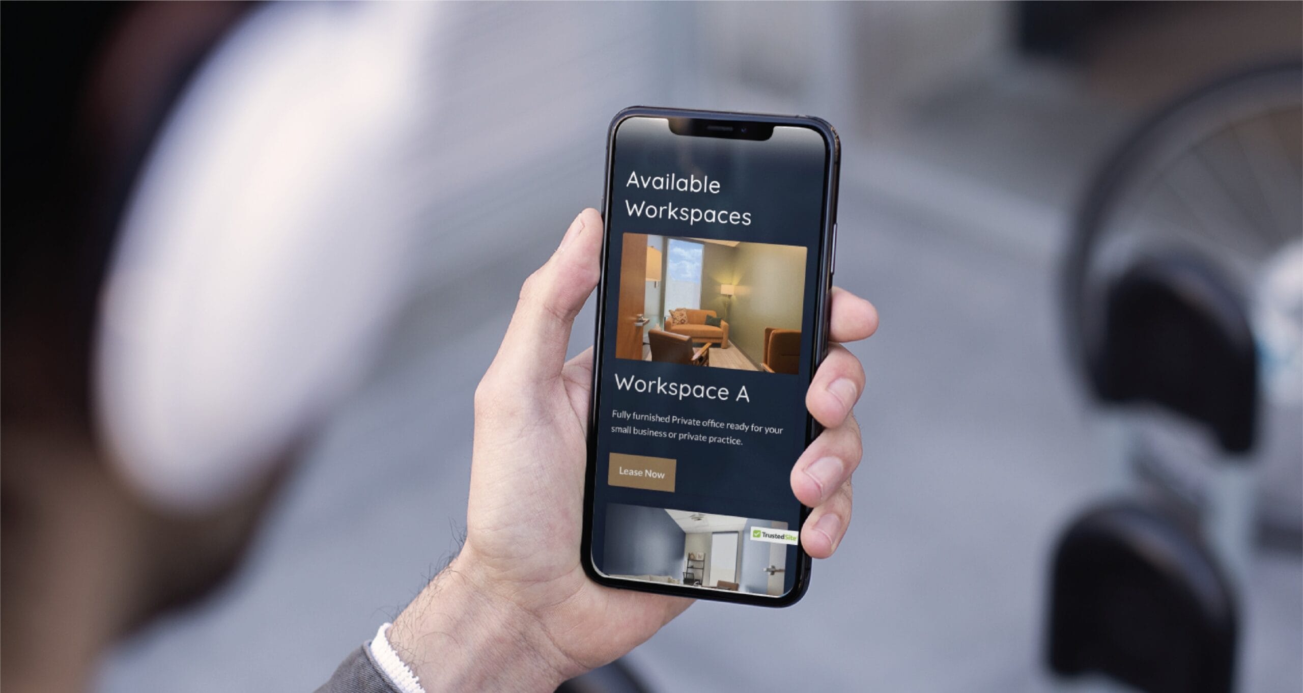 A hand holds a smartphone displaying a workspace booking app, featuring Available Workspaces and details for Workspace A with a modern office photo—perfect for Minnesota businesses focused on website design.