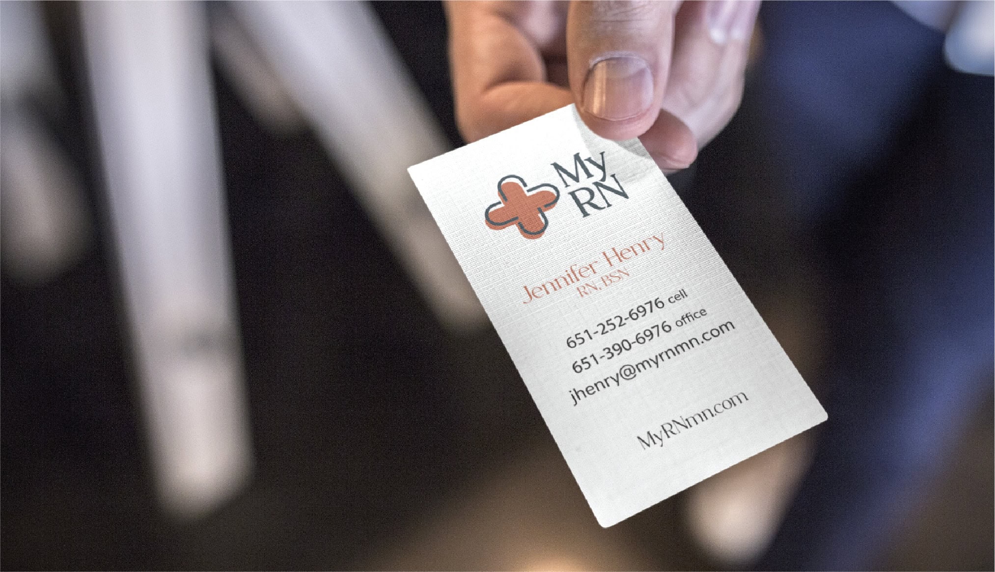 A person holds a My RN business card for Jennifer Henry, RN, BSN, featuring contact information and a website, presented with the professional polish of a stationery design.