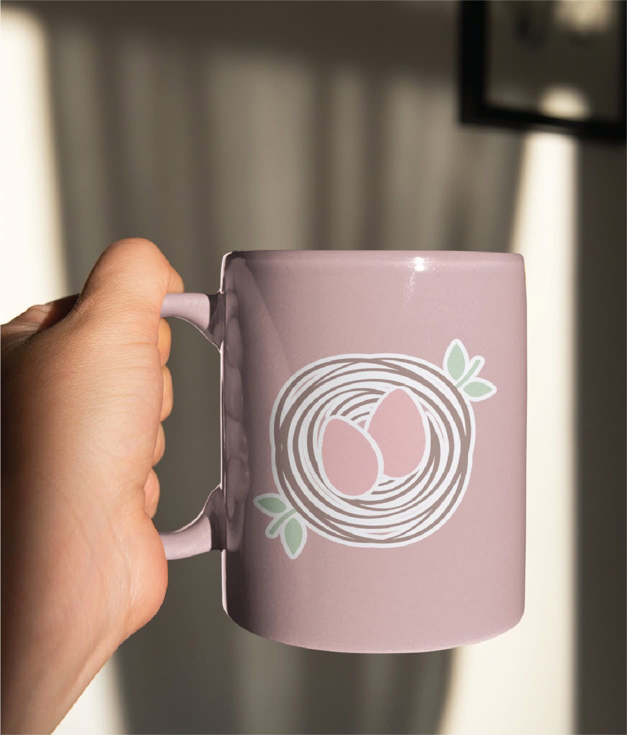 A hand holds a light purple mug featuring a custom logo design of two eggs in a nest, the perfect companion for a newborn sleep consultant.