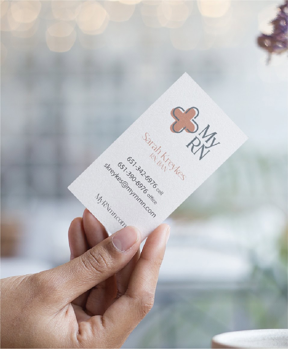 A hand holds a custom stationery business card for Sarah Kreykes, RN, BAN, featuring the My RN logo, contact information, and website for her Minnesota RN services.