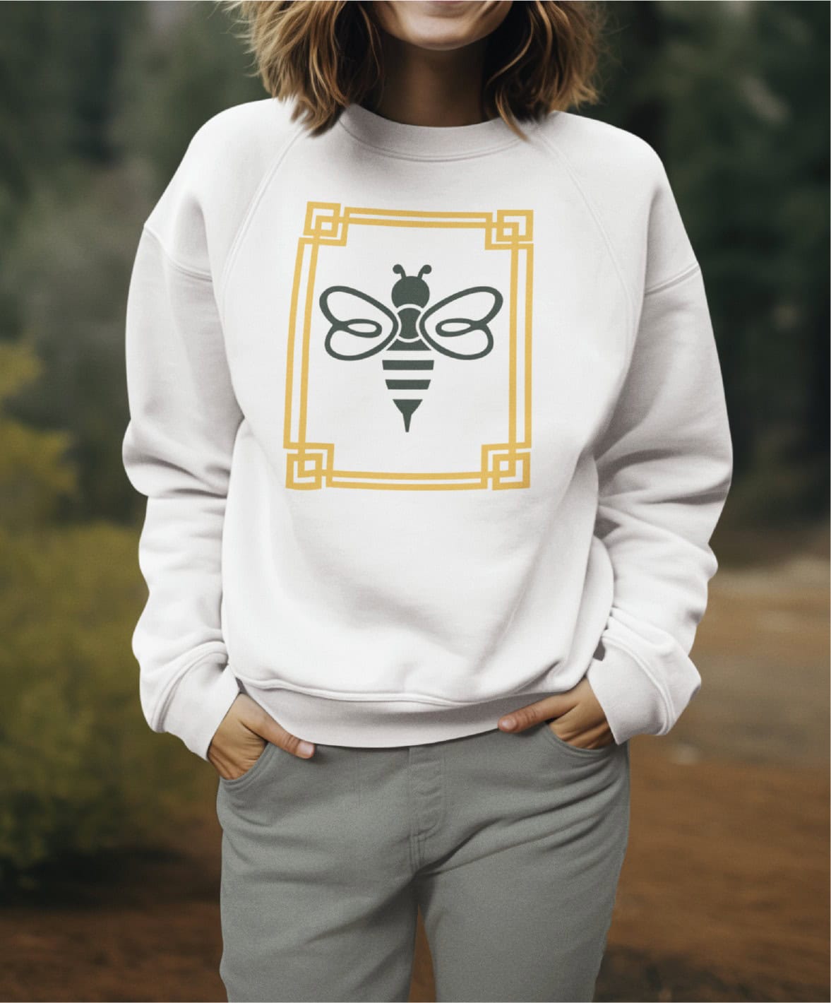 A person wears a white sweatshirt featuring a stylized bee illustration inside a yellow geometric frame that resembles a professional logo design.