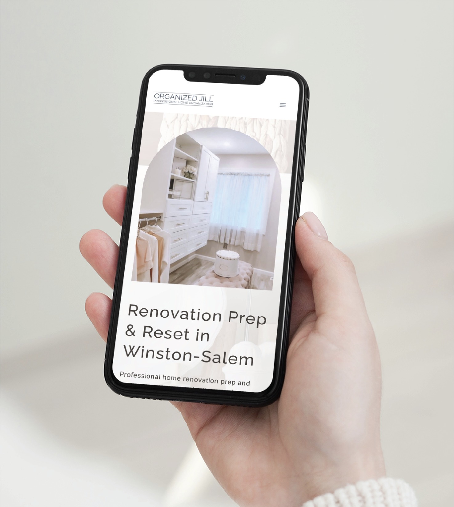 A hand holds a smartphone displaying the Organized Jill website, showcasing professional organizers in Winston-Salem with a closet photo and the text Renovation Prep & Reset.
