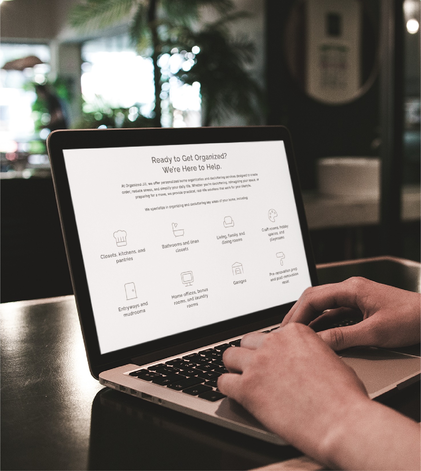 A person uses a laptop to view the Organized Jill website, which showcases professional organizers in Virginia through room categories like kitchens, pantries, closets, offices, and garages.