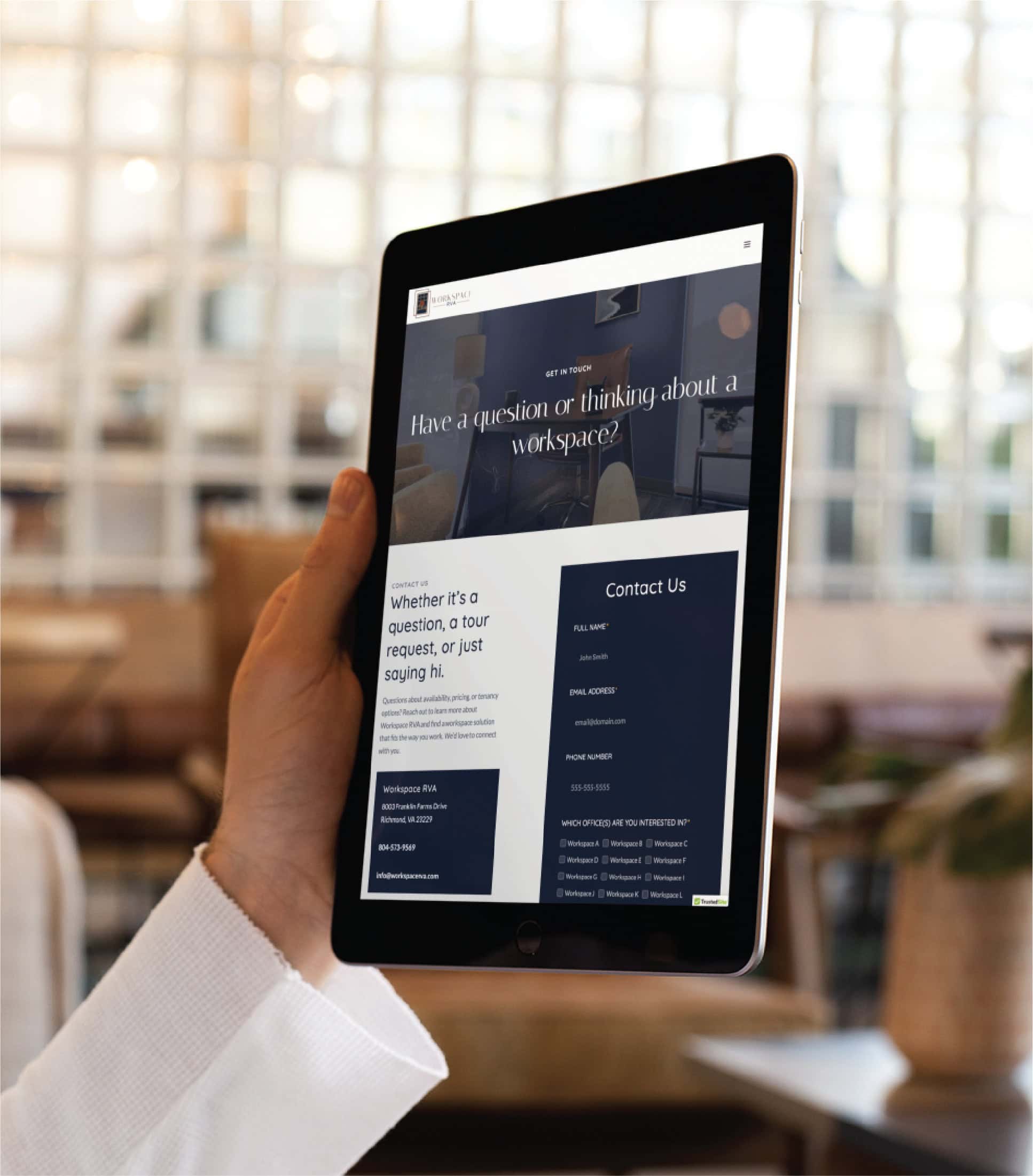 A person holds a tablet displaying an RN Services contact webpage with a form and information, set in a modern Minnesota indoor space with blurred seating and a glass-panel wall in the background.