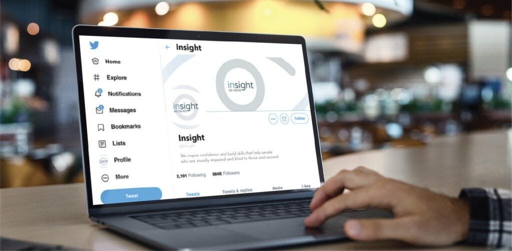 A person’s hand rests on a laptop showing a Twitter profile for Insight, an organization focused on Rhode Island marketing.